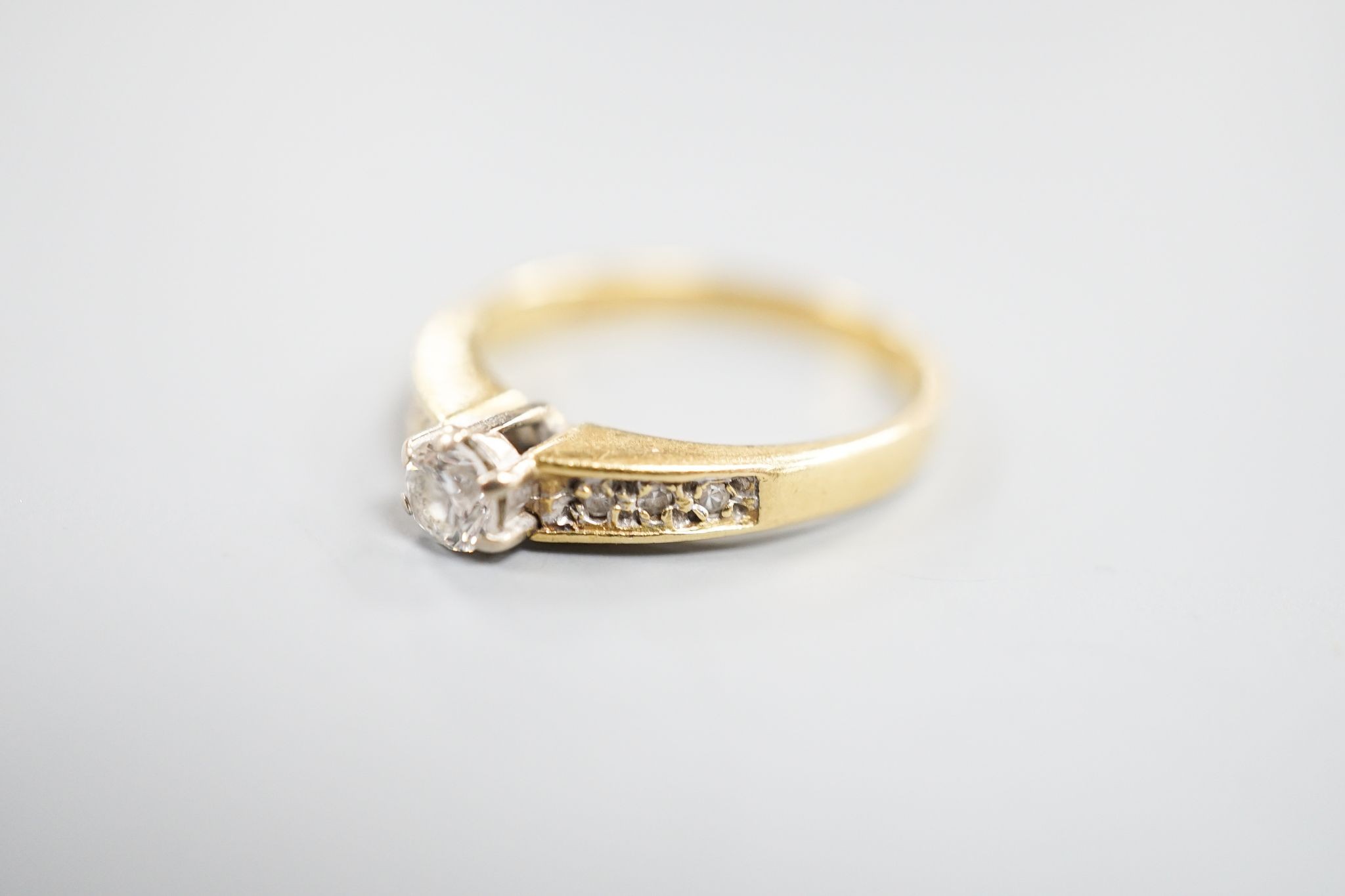 A modern 18ct gold and single stone diamond ring, with diamond set shoulders, size L, gross 2.4 grams.